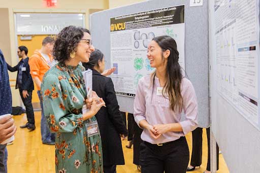 two researchers talking and smiling at a research conference