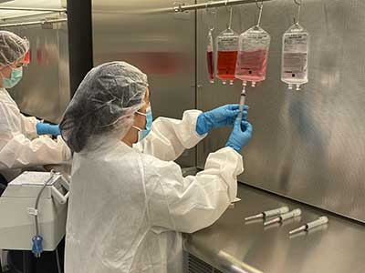 person in lab coat works with a solution in a sterile compounding lab