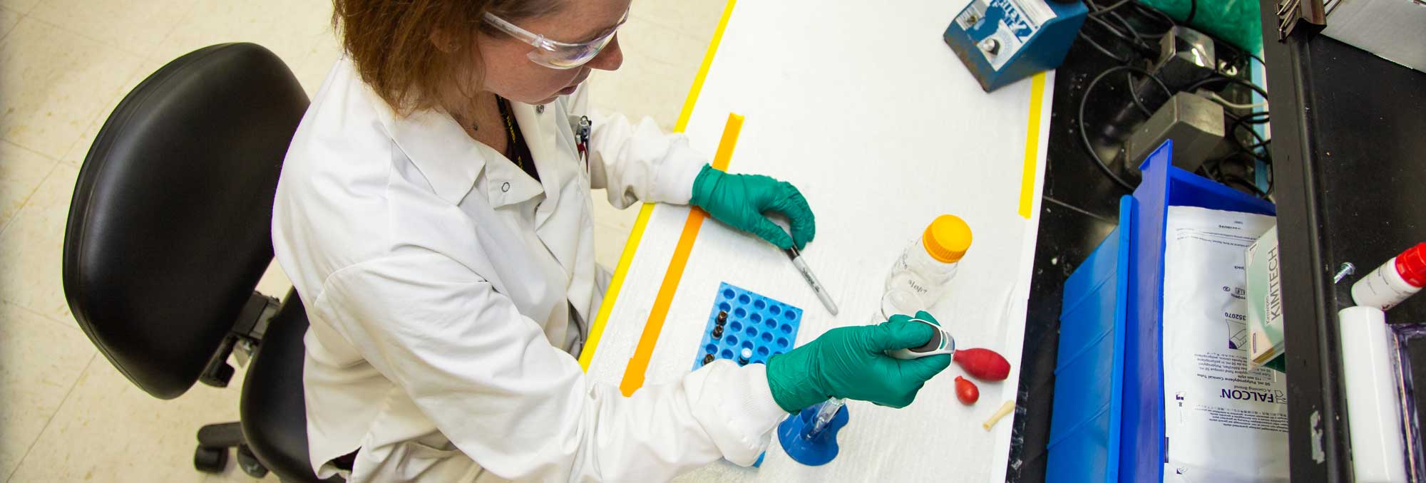 a worker in a lab adding fluid to a test tube