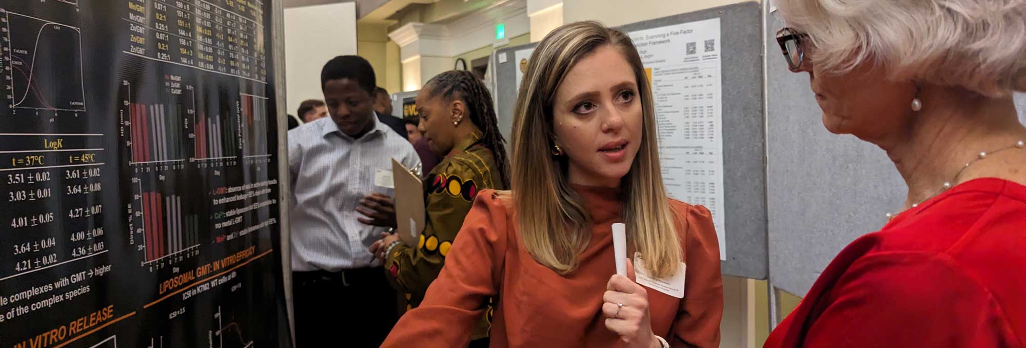 a student presenter speaking to a professor at a research poster session