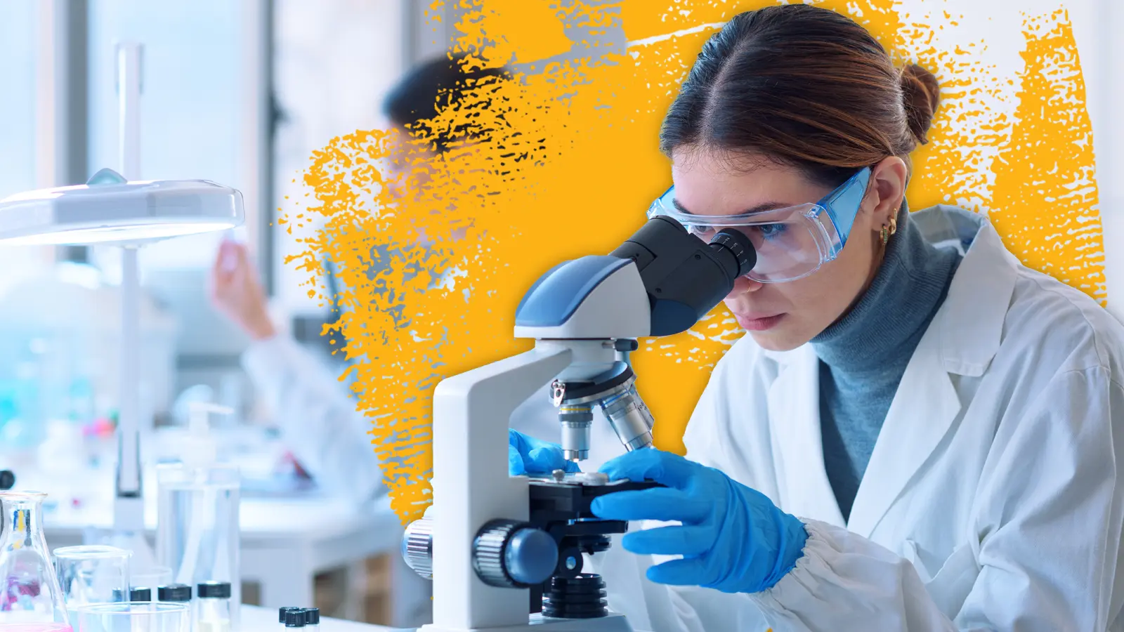 a lab worker dressed in protective wear looks intently into a microscope