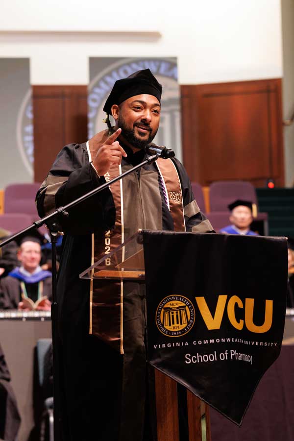 Rahil Syed in graduation regalia addresses the audience at the VCU School of Pharmacy Class of 2026 Hooding & Diploma Ceremony.