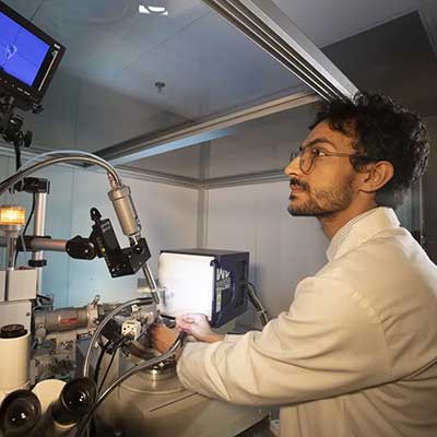 Mohammed Alawadh using scientific equipment looking up at a screen above him.