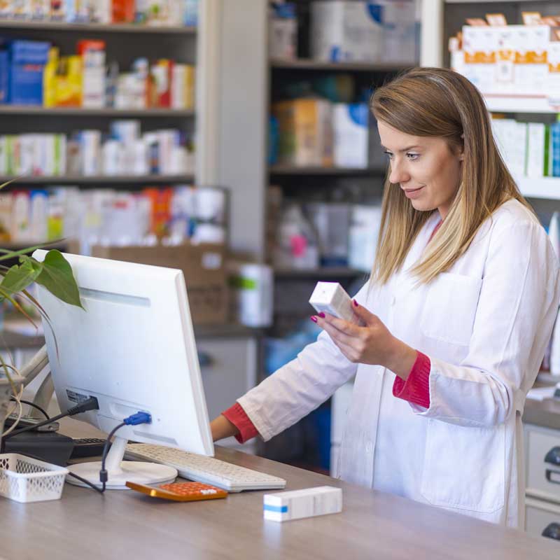 a pharmacy worker checks the price of medication in a computer