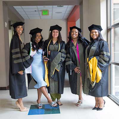 Five pharmacy students in graduation cap and gown.