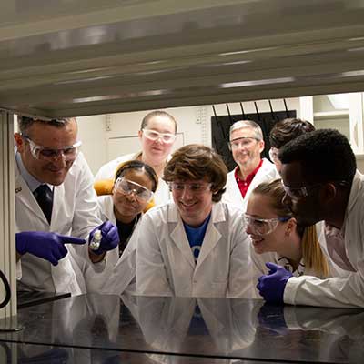 Group of students in lab looking at container of medication.