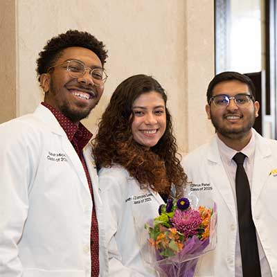 Three V C U pharmacy students in white coats.