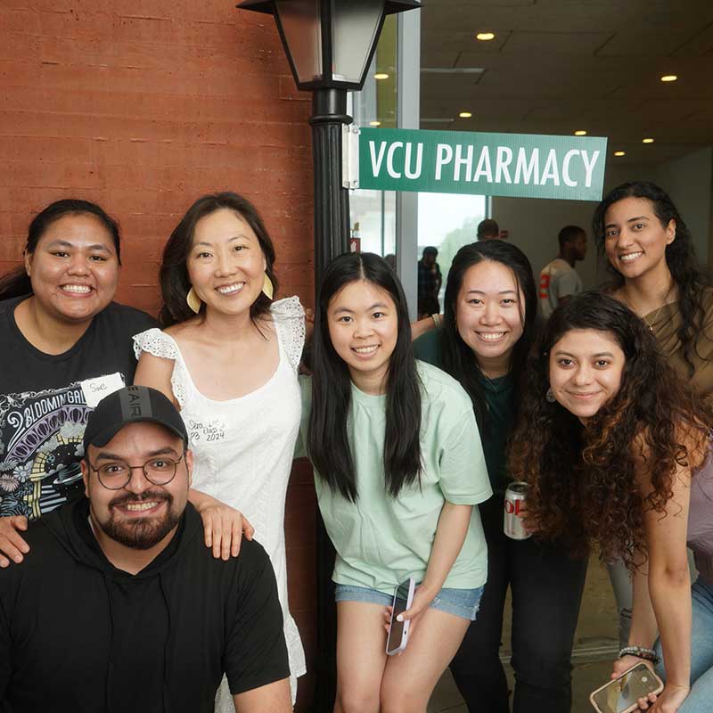 V C U Pharmacy students posing under V C U Pharmacy street sign.