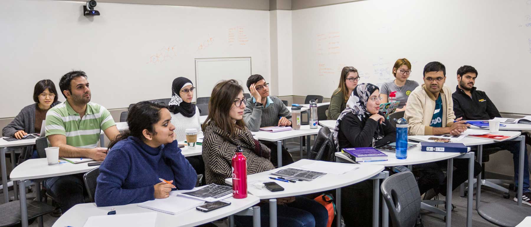 Pharmacy students sit a classroom tables.