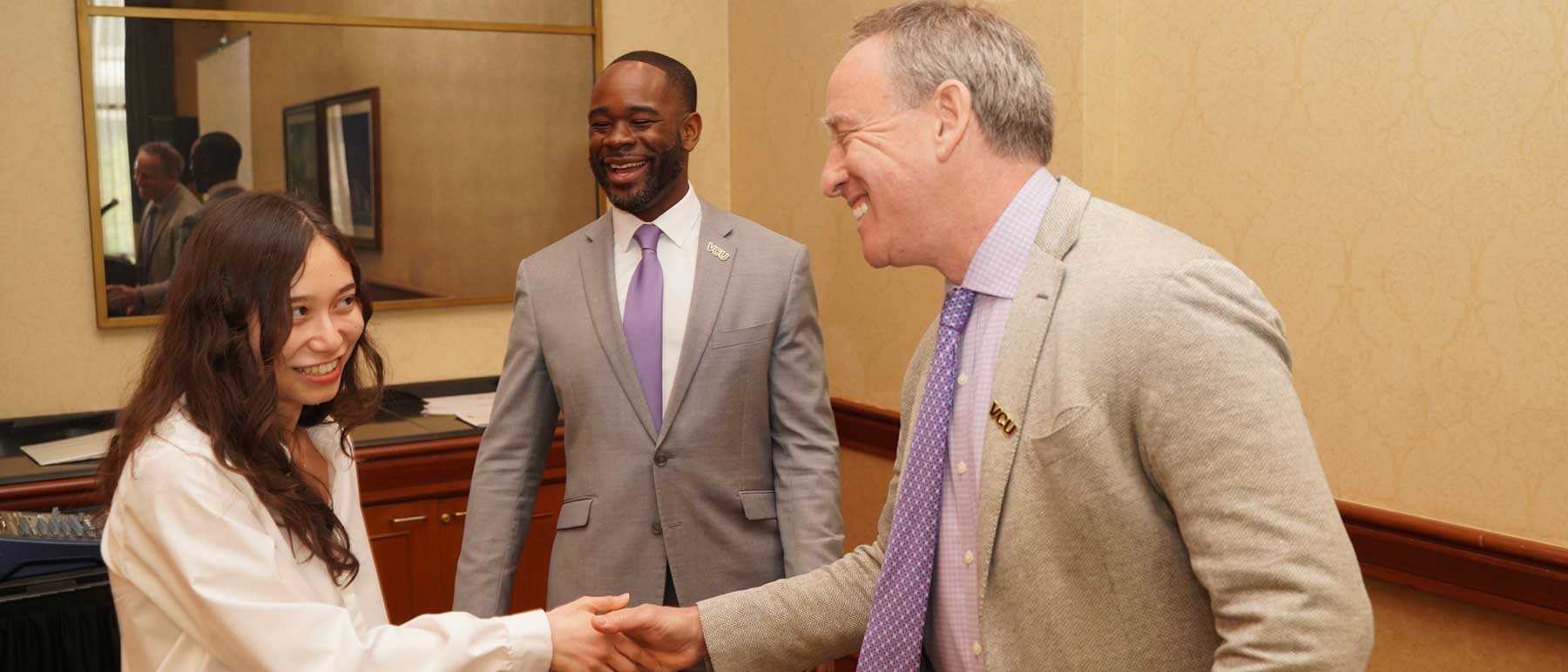 A professor shakes hands with a student.