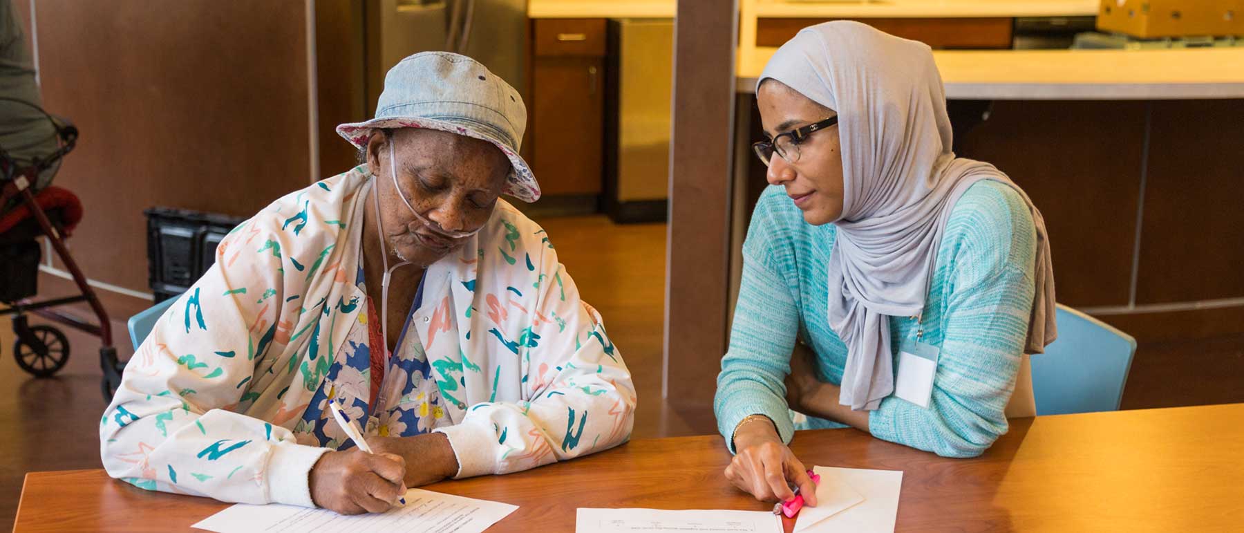 A student sitting with a patient filling out paperwork.