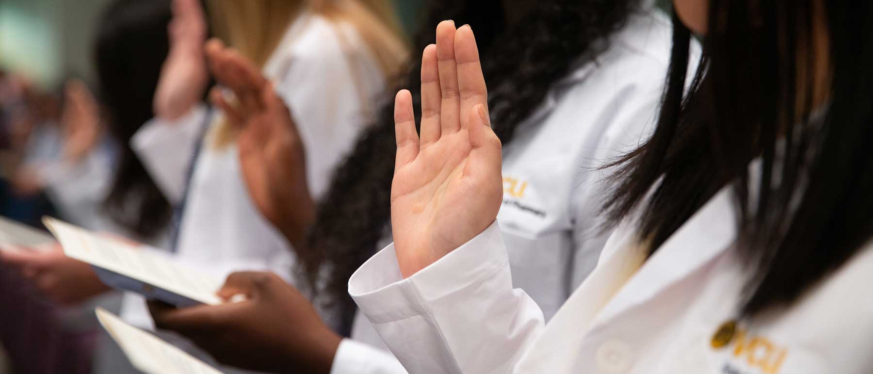 Pharmacy students raise hands to take pharmacy oath.