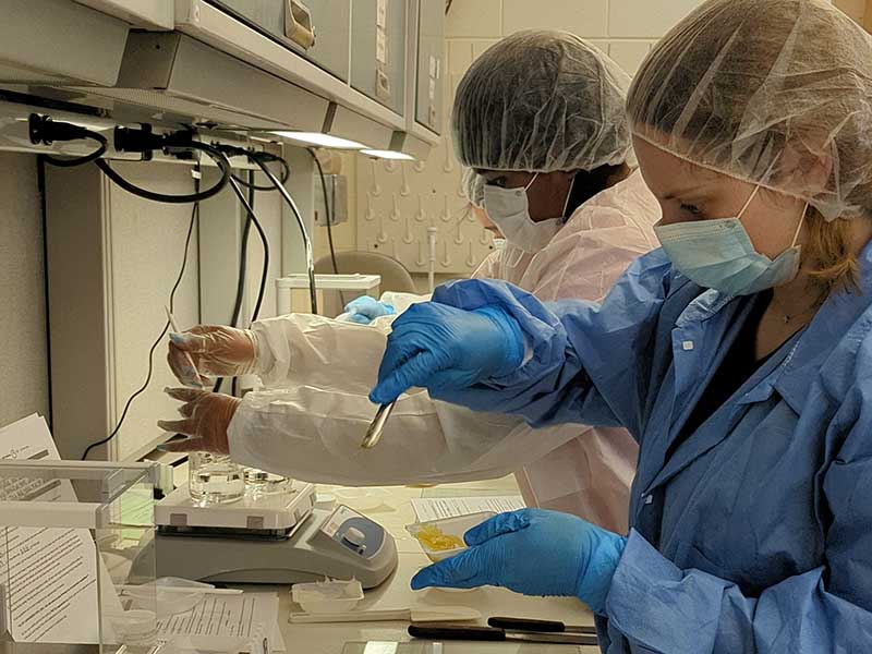 two researchers wearing sterile lab covering making balm.