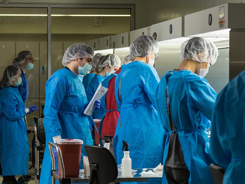 A group of researchers wearing sterile coverings working in a research lab.