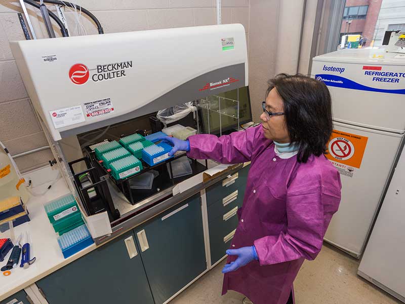 A researcher wears sterile lab covering working with lab equipment.