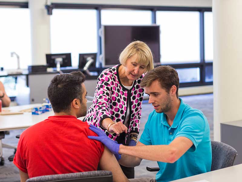 A professor observes a student giving a shot to another student.