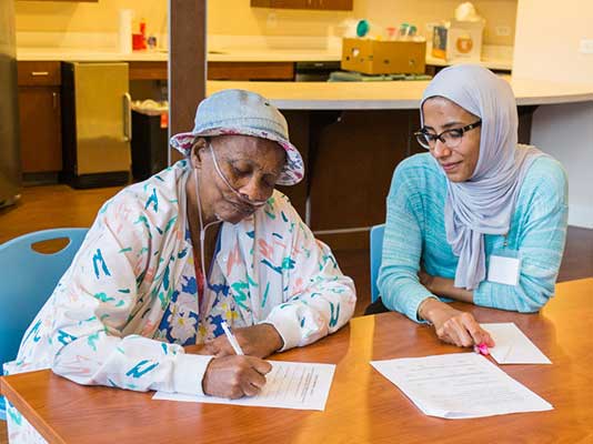 a health care worker at a clinic assists an elderly patient filling out paperwork