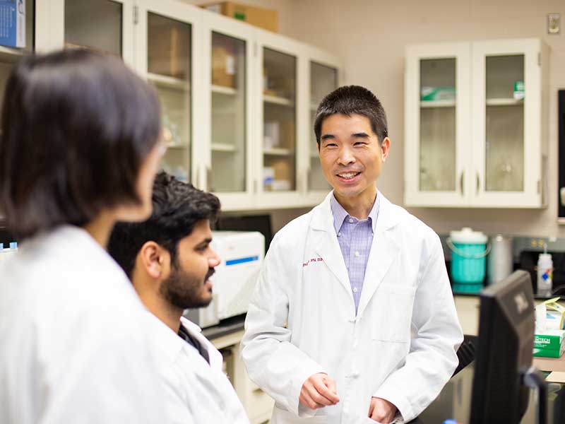 A researcher talks to students in a research lab.