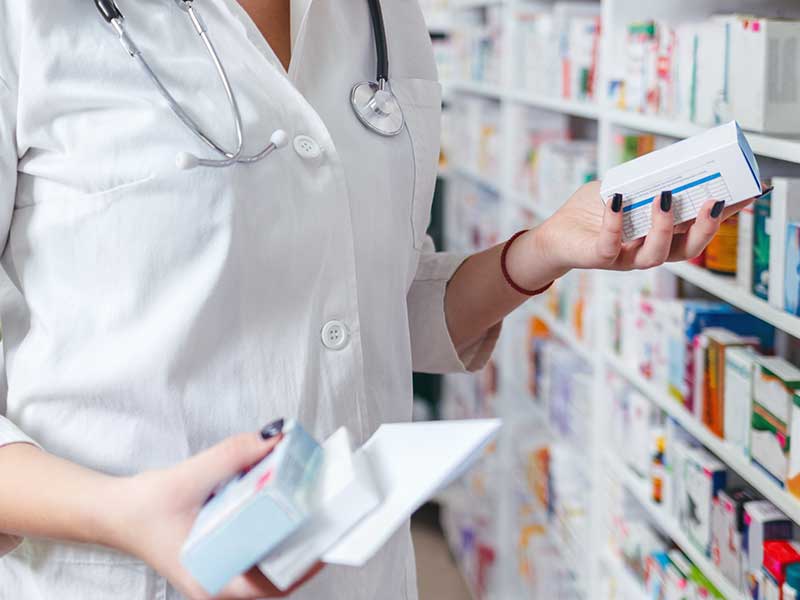 a pharmacy worker in a pharmacist examines a box of medication