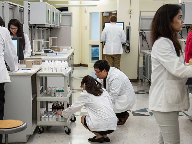 Researchers in a lab grabbing item off of shelf.