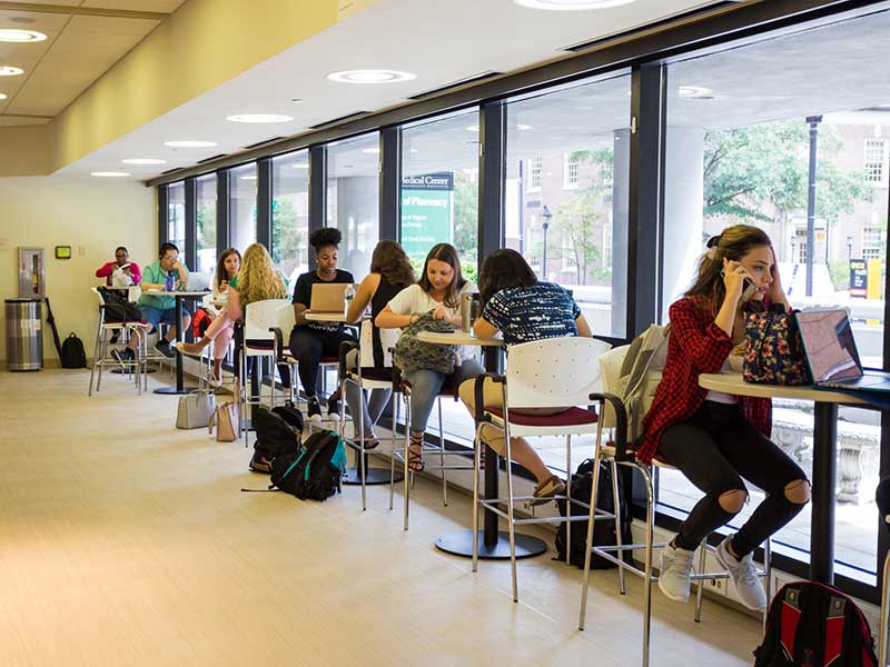 Students sit a table in V C U school of pharmacy lobby.