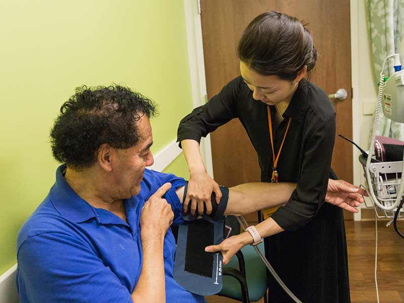 A student takes the blood pressure of a patient.