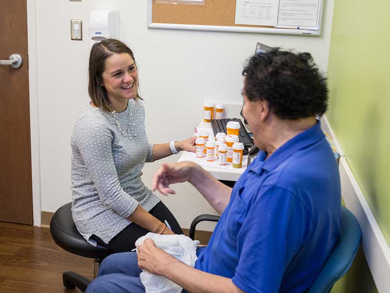 A pharmacists sits with a patient in clinic.