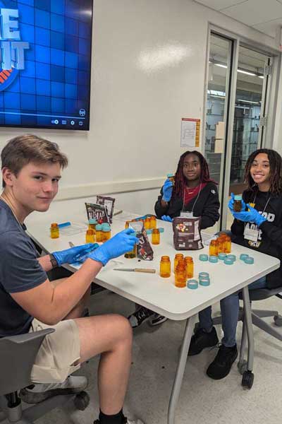 Students finish a Minute to Win It pill counting exercise with M&M's in a lab
