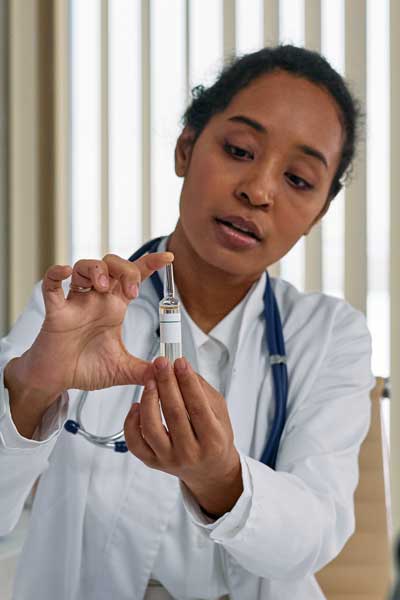 a pharmacist holds up a syringe full of medicine