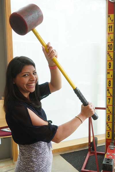 A student swings big carnival hammer while playing carnival game.