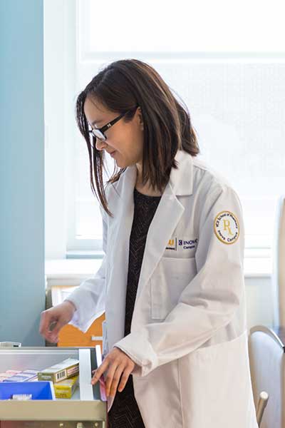 Women in white lab coat looks down at lab materials.